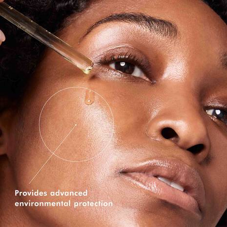 SkinCeuticals  C E Ferulic Close-up of a woman applying a dropper of skincare product to her face with text 'Provides advanced environmental protection'.